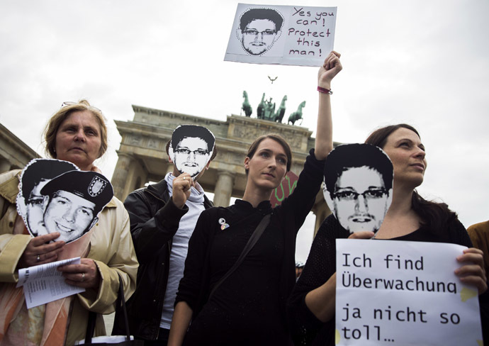 People hold placards in support of former U.S. spy agency contractor Edward Snowden during a protest in front of Brandenburg Gate in Berlin, July 4, 2013. (Reuters/Thomas Peter)
