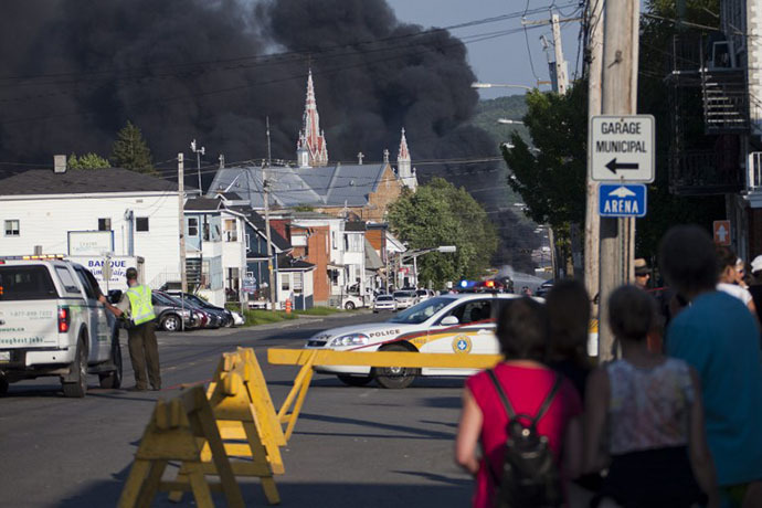 Residents watch rising smoke after a freight train loaded with oil derailed in Lac Megantic in Canada's Quebec province on July 6, 2013, sparking explosions that engulfed about 30 buildings in fire. (AFP Photo / FranÃois Laplante-Delagrave)