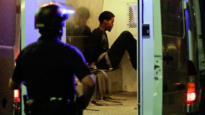 A Los Angeles police officer looks on as an arrested individual sits in the back of a van after a peaceful protest supporting Trayvon Martin turned unlawful in the Leimert Park neighborhood Los Angeles, California, July 15, 2013.(Reuters / Jason Redmond)