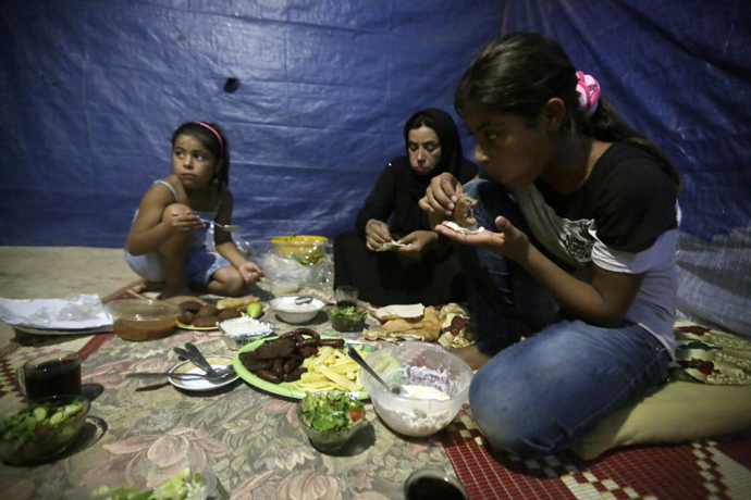 Fatima (C) a Syrian refugee widow, who lost her husband during the fighting in Homs, and her daughters have their Ramadan diner in their makeshift room in a neighbourhood of the Lebanese coastal city of Tripoli that hosts refugees on July 15, 2013 (AFP Photo / Joseph Eid) 