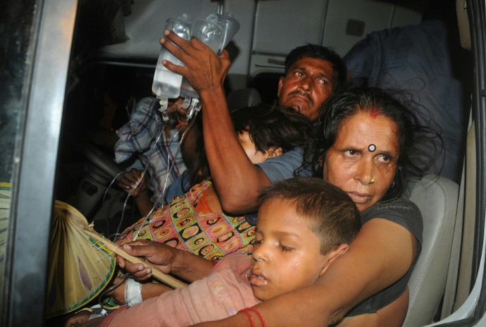In this photograph taken on July 16, 2013 an Indian family, with their son who fell ill after consuming a free school meal, are transported outside the Patna Medical College Hospital in Patna. (AFP Photo)