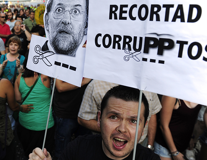 People hold a poster reading "Let's cut corrupted" and a picture of Spanish Prime Minister Mariano Rajoy as they protest, on their way to the headquarters of the PP, blocked by the police, in Madrid on July 18, 2013. (AFP Photo / Dominique Faget)