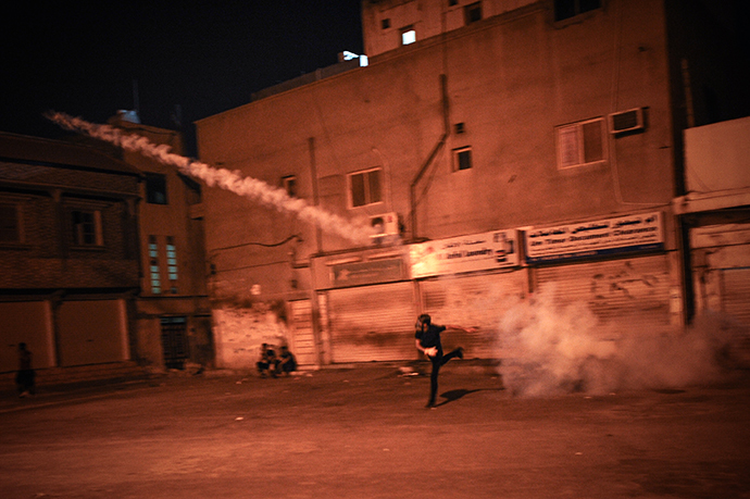 A Bahraini protestor throws back a tear gas canister fired by riot police during clashes following a protest to demand more rights and against the ruling regime in the village of Diraz, West of Manama, on July 19, 2013. (AFP Photo / Mohammed Al-Shaikh)
