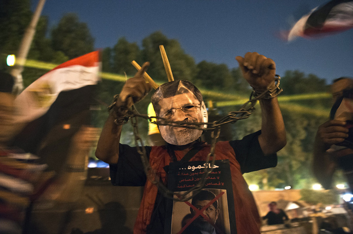 An man wearing a mask of ousted president Mohamed Morsi shows his handcuffed hands outside the presidential palace in Cairo on July 19, 2013 (AFP Photo / Khaled Desouki) 