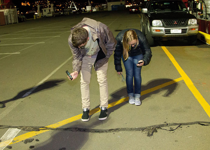 Students photograph a crack on the ground on the wharf on the waterfront after a 6.5 magnitude earthquake hit Wellington on July 21, 2013.(AFP Photo / Marty Melville)