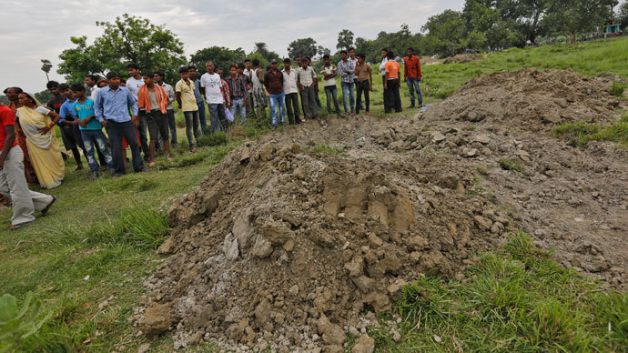 Villagers stand next to mass graves of the school children who died after consuming contaminated meals given to them at a school on Tuesday, at Chapra district in the eastern Indian state of Bihar July 18, 2013.(Reuters / Adnan Abidi)