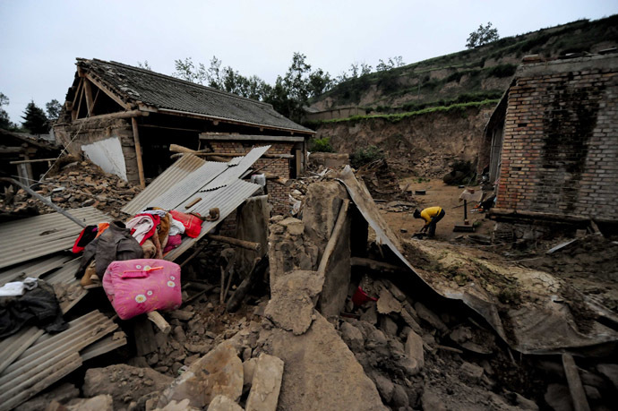 A woman (R) works beside damaged houses in Meichuan township in Dingxi, in northwest China's Gansu province, on July 23, 2013. (AFP Photo)