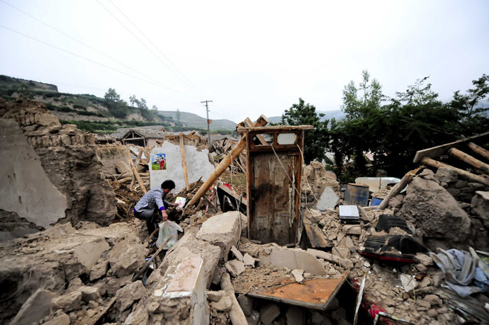 A woman (L) works beside damaged houses in Meichuan township in Dingxi, in northwest China's Gansu province, on July 23, 2013. (AFP Photo)