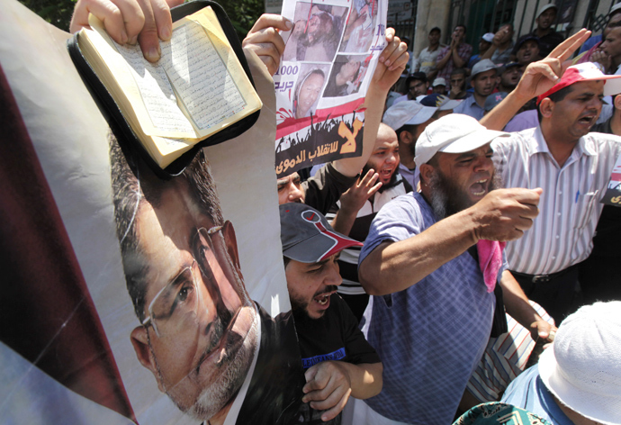 Members of the Muslim Brotherhood and supporters of deposed Egyptian President Mohamed Mursi shout slogans while holding posters of Mursi and copies of the Koran during a protest in Cairo July 22, 2013 (Reuters / Mohamed Abd El Ghany)