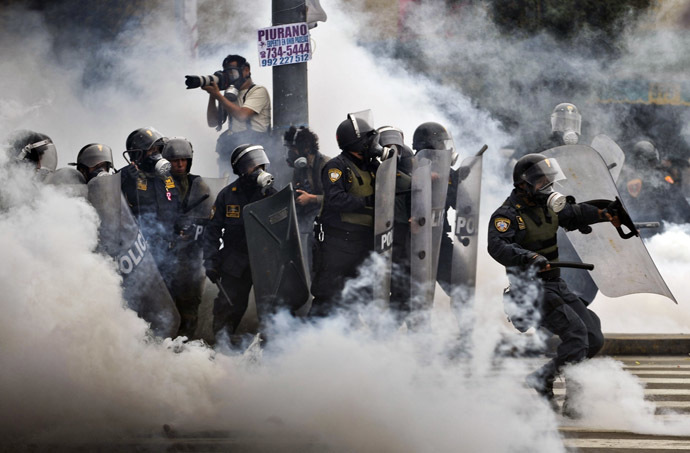 Riot policemen stand in a tear gas cloud during clashes within a student and workers protest against the government, in Lima on July 27, 2013. (AFP Photo/Ernesto Benavides)