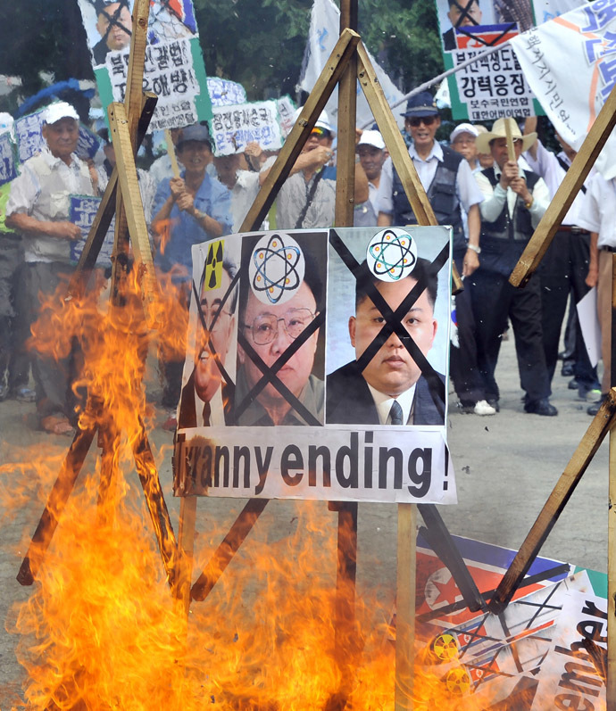 South Korean conservative activists burn portraits of North Korea's founder Kim Il-Sung (R), late leader Kim Jong-Il (C) and present leader Kim Jong-Un during an anti-North Korea rally at a park in Seoul on July 27, 2013 to mark the 60th anniversary of ceasefire agreement and UN forces' participation in the Korean War. (AFP Photo/Jung Yeon-Je)