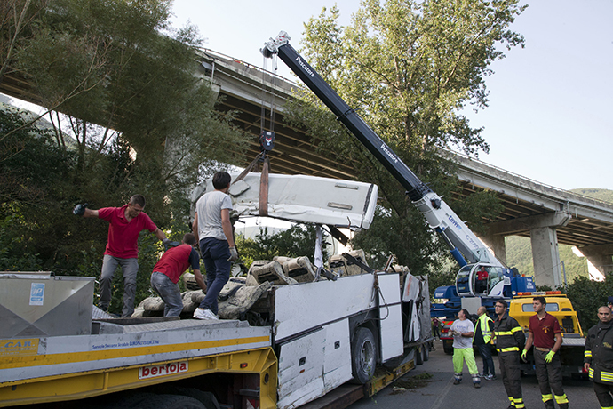 Workers remove the wreck of a bus on July 29, 2013 near Baiano, following a crash the day before on the road between Monteforte Irpino and Baiano, southern Italy. (AFP Photo / Carlo Hermann)