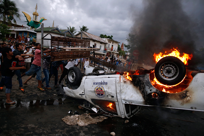 Protesters throw a bench onto a burning police vehicle following a brief clash at the end of election day in Phnom Penh July 28, 2013 (Reuters / Damir Sagolj) 