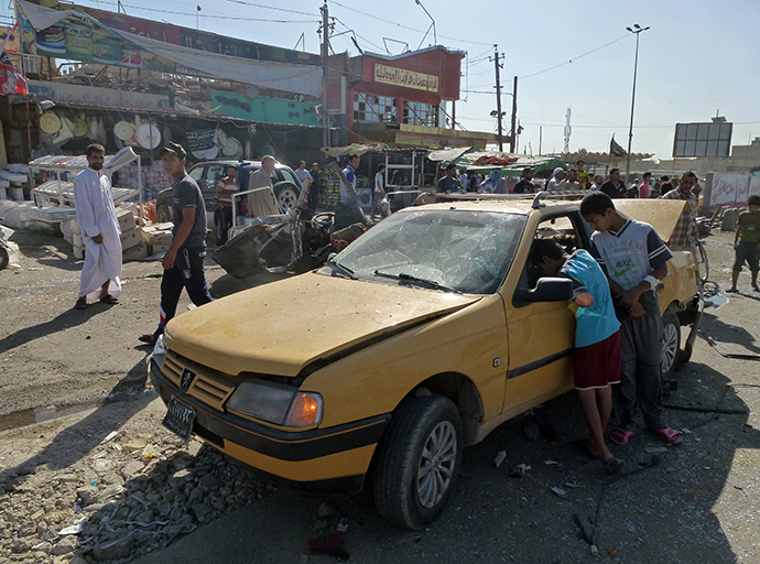 Iraqis inspect the site of a car bomb explosion in the impoverished district of Sadr City in Baghdad on July 29, 2013, after 11 car bombs hit nine different areas of Baghdad, seven of them Shiite-majority, while another exploded in Mahmudiyah to the south of the capital. (AFP Photo / Ahmad Al-Rubaye)