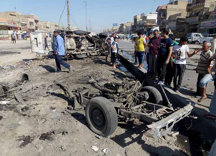 Iraqis inspect the site of a car bomb explosion in the impoverished district of Sadr City in Baghdad on July 29, 2013, after 11 car bombs hit nine different areas of Baghdad, seven of them Shiite-majority, while another exploded in Mahmudiyah to the south of the capital. (AFP Photo / Ahmad Al-Rubaye)