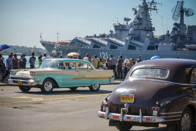 Vintage US-made cars pass by as Cubans watcht the "Moskva" Russian guide missile cruiser arriving at Havana's harbour, on August 3, 2013.(AFP Photo / Adalberto Roque)