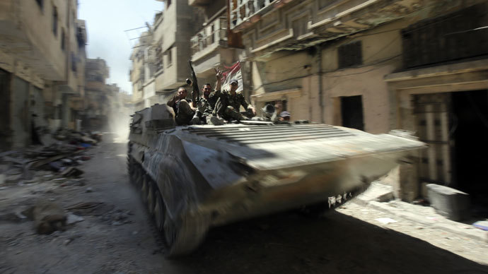 Soldiers of the Syrian government forces patrol on a tank in a devastated street on July 31, 2013 in the district of al-Khalidiyah in the central Syrian city of Homs. (AFP Photo / Joseph Eid)