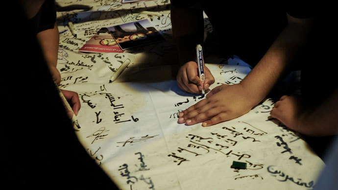 Bahraini protester signs a petition, set up in a street during a rally in central Manama early on July 30, 2013, to collect signatures to support " Bahrain Rebellion " a call going around Bahrain for a mass demonstration on August 14.(AFP Photo / Mohammed Al-Shaikh)