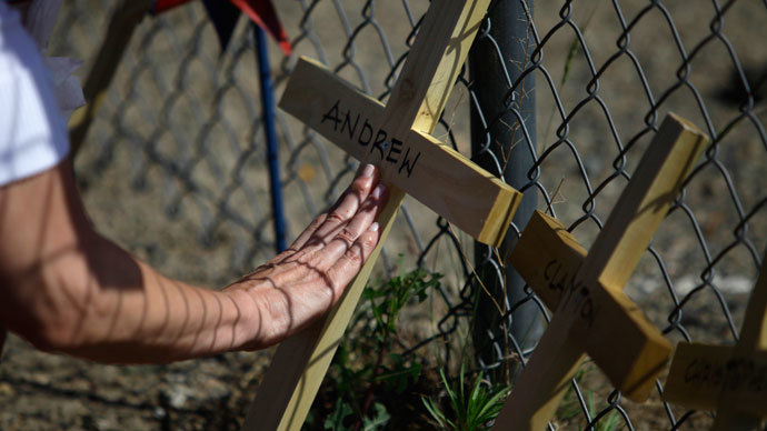 Linda Lambert touches the cross displayed for her nephew and Hot Shot Firefighter Andrew Ashcraft, at a makeshift memorial for the 19 firefighters who perished battling a fast-moving wildland fire, outside the Granite Mountain Interagency Hot Shot Crew fire house in Prescott, Arizona July 2, 2013.(Reuters / Joshua Lott)