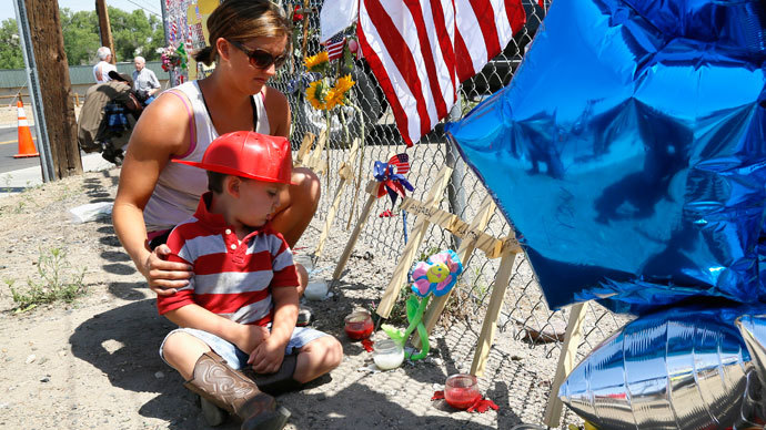 Casen Beyea, 3, wearing a toy fireman helmet looks at the cross for Andrew Ashcrast with his mother Christine at a memorial for the 19 firefighters killed in the nearby wildfire, in Prescott, Arizona July 2, 2013.(Reuters / Rick Wilking)