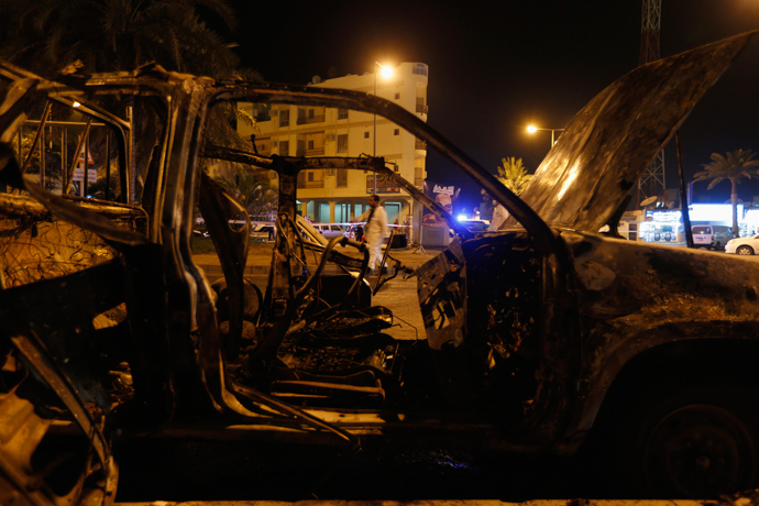 A bomb specialist (C) looks for evidence in front of an exploded vehicle in Budaiya, west of Manama August 3, 2013 (Reuters / Hamad I Mohammed)