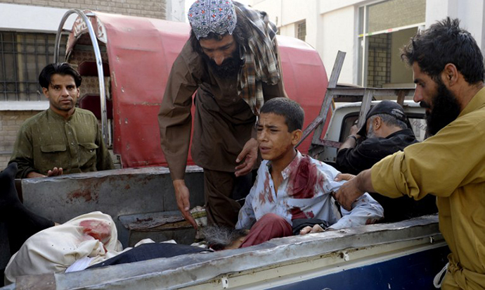 Pakistani bystanders help an injured Muslim youth as he sits in a pickup truck amidst bodies outside a hospital in Quetta on August 9, 2013, following an attack by gunmen on a mosque. (AFP Photo / Banaras Khan)