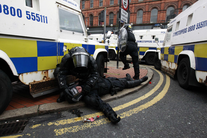 A police officer is tended to by a colleague after Loyalist protesters attacked the police with bricks and bottles as they waited for a republican parade to make its way through Belfast City Centre, August 9, 2013. (Reuters/Cathal McNaughton)
