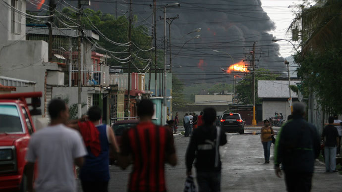 Local residents look towards the refinery of Guaraguao after a fire broke when a lightning struck a treatment pond, in Puerto la Cruz, state of Anzoategui, 220 km east of Caracas, on August 11, 2013.(AFP Photo / Jose Manuel Rondon)