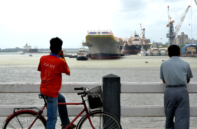 Indian locals watch as tugboats guide the indigenously-built aircraft carrier INS Vikrant as it leaves the dock of the Cochin Shipyard after the launch ceremony in Kochi on August 12, 2013 (AFP Photo / Manjunath Kiran)