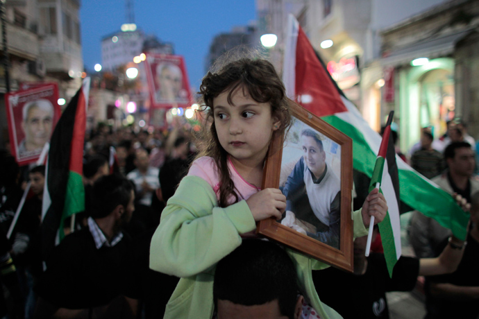 A girl holds a portrait of a Palestinian held in an Israeli jail during celebrations after a deal to end a prisoners hunger strike was agreed, in the West Bank city of Ramallah (Reuters)