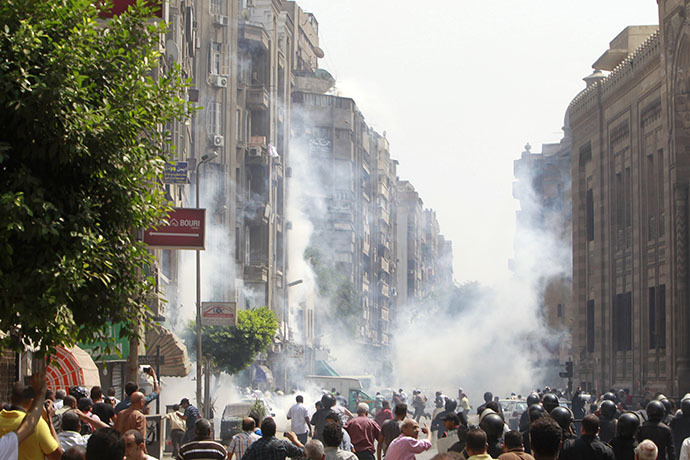 Supporters of ousted Egyptian President Mohamed Mursi run away from tear gas while local residents are seen in the foreground during clashes in central Cairo August 13, 2013. (Reuters / Mohamed Abd El Ghany)