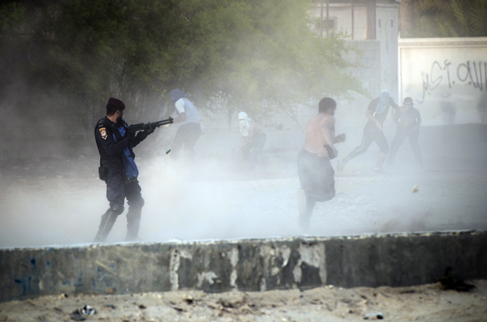 A Bahraini riot policeman ( L ) fires bird shot toward anti-government protestors during demonstration against the ruling regime in the village of Shakhora, west of Manama, on August 14, 2013 (AFP Photo / Mohammed Al-Shaikh) 