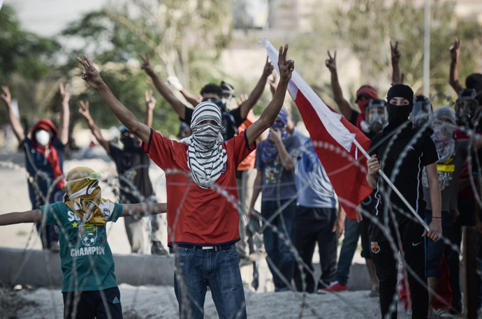 Bahraini protestors flashing "V" sign for victory, stand behind barbed wire placed by riot police during demonstration against the ruling regime in the village of Shakhora, west of Manama, on August 14, 2013 (AFP Photo / Mohammed Al-Shaikh) 