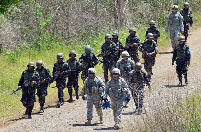 Philippine (L) and US (R) troops walk to their base after conducting a squad live fire exercise as part of the annual joint Philippine-US military exercise at Fort Magsaysay in Nueva Ecija province, north of Manila on April 11, 2013. (AFP Photo/Ted Aljibe)
