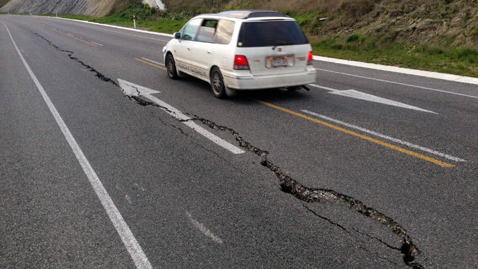A car drives past a crack in a road after an earthquake on the outskirts of the town of Seddon in the Marlborough region, on New Zealand's South Island August 16, 2013.(Reuters / Anthony Phelps)