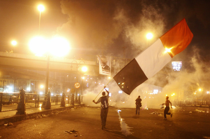 Supporters of Egyptian president Mohamed Mursi waving a national flag run from tear gas during clashes with riot police at the 6th October Bridge in the Ramsis square area in central Cairo July 15, 2013. (Reuters/Asmaa Waguih)