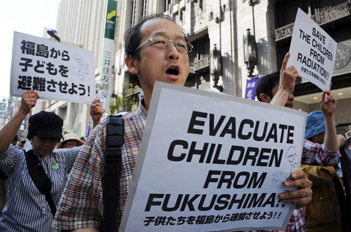 Protesters carry placards as they march in Tokyo's shopping district of Shinjuku on May 18, 2013 calling for the evacuation of children still living in the Fukushima prefecture area. (AFP Photo / Rie Ishii)