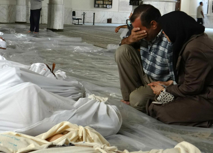 A handout image released by the Syrian opposition's Shaam News Network shows a Syrian couple mourning in front of bodies wrapped in shrouds ahead of funerals following what Syrian rebels claim to be a toxic gas attack by pro-government forces in eastern Ghouta, on the outskirts of Damascus on August 21, 2013. (AFP Photo/Shaam News Network)