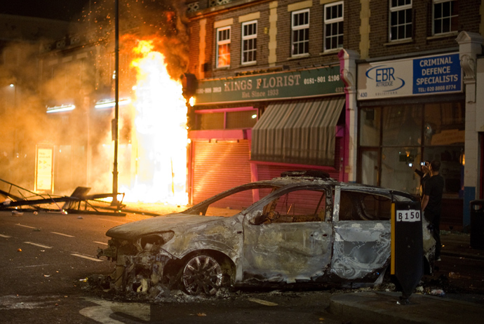 A shop burns as riot police try to contain a large group of people on a main road in Tottenham, north London on August 6, 2011 (AFP Photo / Leon Neal)