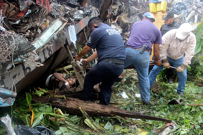 Mexican state policemen helping trapped people after a train, known as "The Beast", derailed near Huimanguillo, Tabasco State, Mexico, on August 25, 2013 (AFP Photo / Tabasco Hoy)