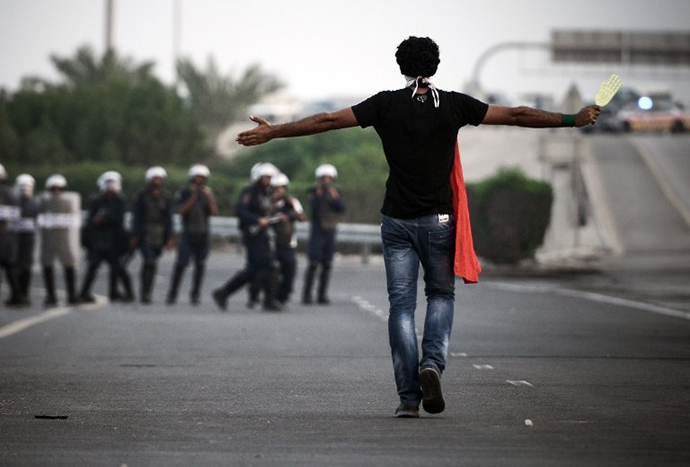 A Bahraini protester stands facing riot police during clashes following the funeral of Sadeq Sabt, in the village of North Sehla, west of Manama, on September 1, 2013. (AFP Photo / Mohammed Al-Shaikh)