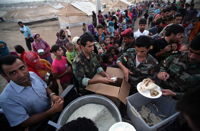 Syrian-Kurdish refugee families queue to get food at the Quru Gusik refugee camp, 20 kilometres east of Arbil, the capital of the autonomous Kurdish region of northern Iraq, on August 27, 2013. (AFP Photo / Safin Hamed)