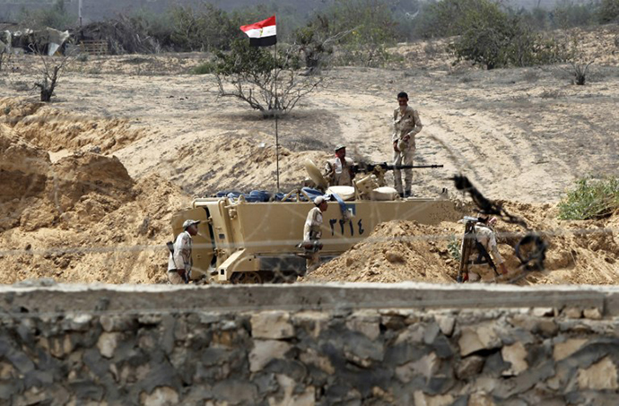 A picture taken from Rafah in the southern Gaza Strip shows Egyptian soldiers on the other side of the border standing guard near an armoured vehicle. (AFP Photo / Said Khatib)