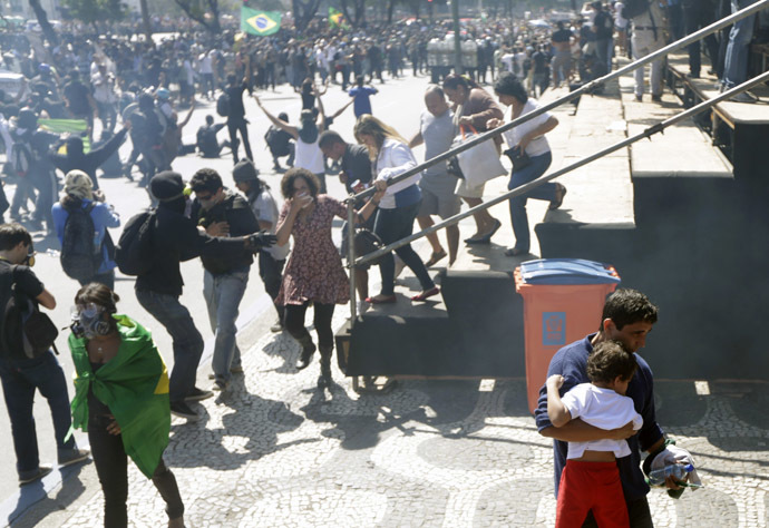 A man walks away with his son as demonstrators clash with riot police near an audience area during a protest as they try to approach a military parade on Brazil's Independence Day in Rio de Janeiro September 7, 2013. (Reuters/Ricardo Moraes)