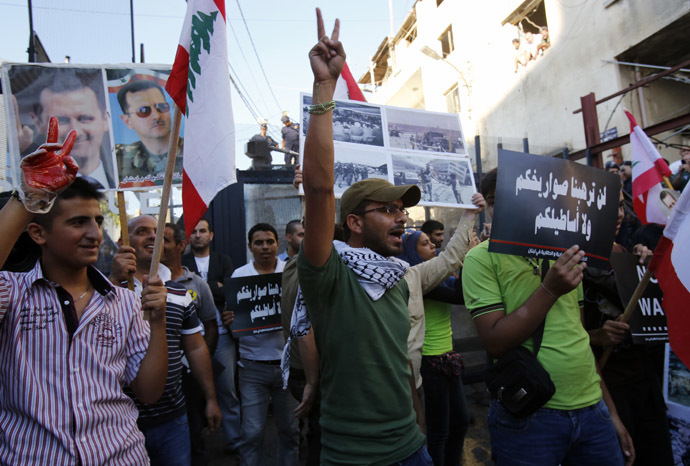 Lebanese supporters of Syrian President Bashar al-Assad (portrait-L) flash the sign for victory as they wave their national flag, during a demonstration near the American embassy, east of Beirut against a possible US military strike on Syria on September 6, 2013. (AFP Photo)
