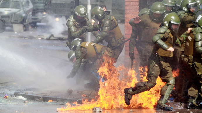 A riot policeman (L) is helped by fellow policemen after catching fire from a molotov cocktail bomb during a protest marking the 1973 military coup in Santiago, September 8, 2013.(Reuters / Ivan Alvarado)