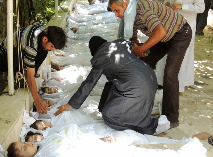 A woman mourning over a body wrapped in shrouds laid out in a line on the ground with other victims which Syrian rebels claim were killed in a toxic gas attack by pro-government forces in eastern Ghouta, on the outskirts of Damascus on August 21, 2013.(AFP Photo / Shaam News Network )