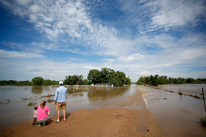 Allison Wold of Denver, Colorado and her nephew, Jack Wold, take in a flooded ranch home with John Brinckerhoff, also of Denver after heavy flooding September 14, 2013 near Dearfield, Colorado (AFP Photo / Marc Piscotty)