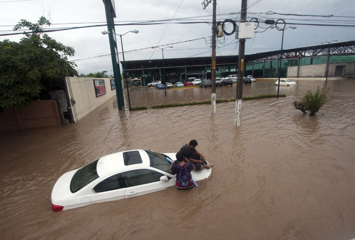 Two men wait for help in a flooded street in Acapulco, Guerrero state, Mexico, after heavy rains hit the area on September 16, 2013. (AFP Photo/Pedro Pardo)