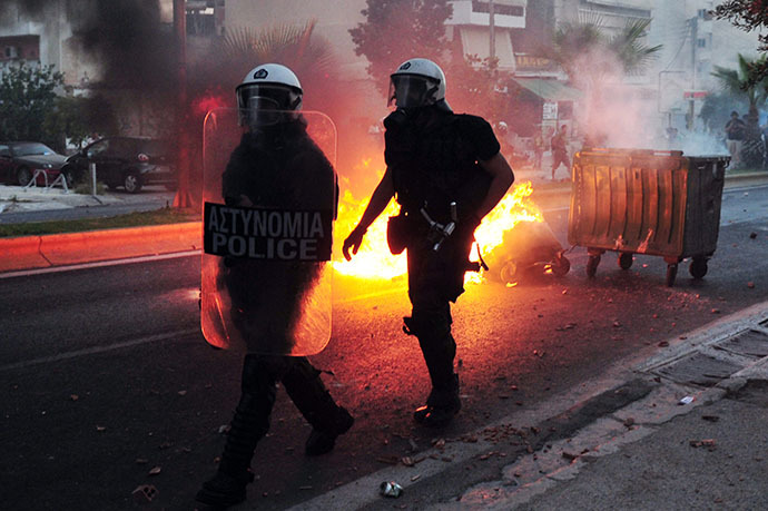 Police advance past a burning barricade as they clash with anti-fascist protesters in the western Athens working class suburb of Keratsini on September 18, 2013, after a leftist musician was murdered by a suspected neo-Nazi. (AFP Photo / Louisa Gouliamaki)